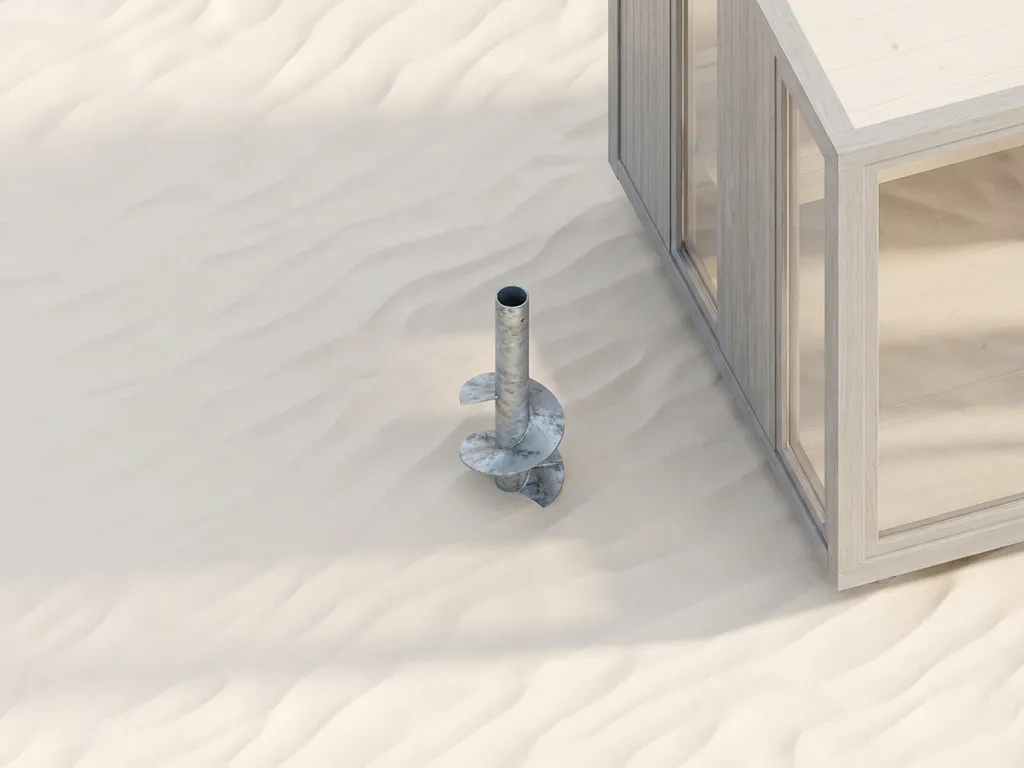 schroeffundering-staal-gegalvaniseerd-zand-cabin.jpg Gegalvaniseerde stalen schroeffundering met spiraalbladen in wit zand naast moderne cabine, bovenaanzicht met minimalistische compositie