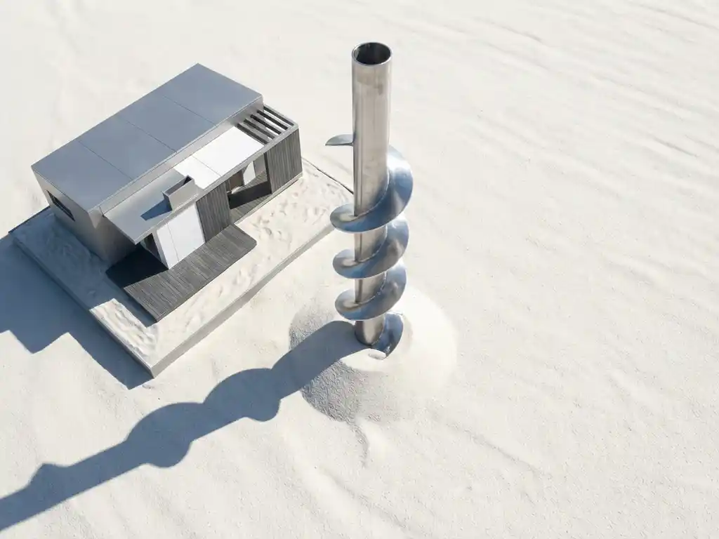 Stalen schroefpaalfundering met spiraalvormige bladen naast modern bungalowmodel op wit zand, bovenaanzicht met dramatische belichting