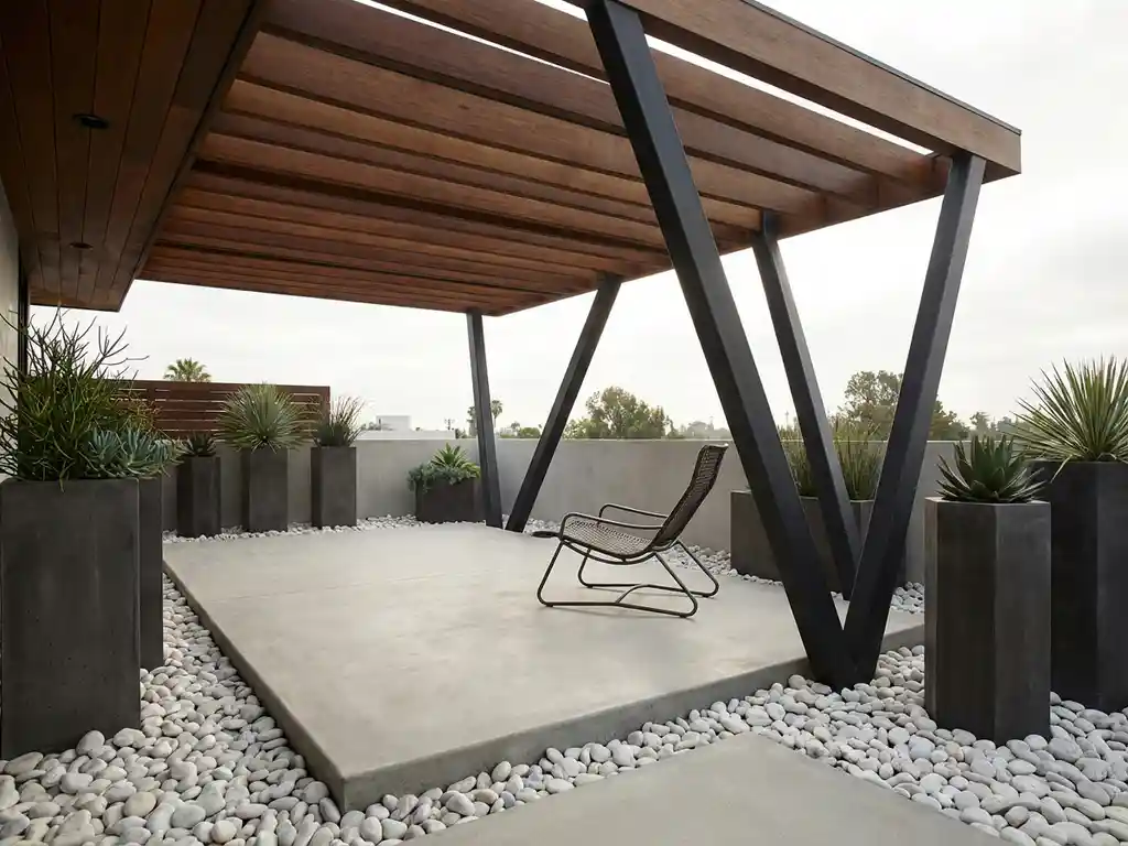 Houten terrasoverkapping met geometrische stalen balken boven betonnen patio, moderne stoel en witte grind accenten