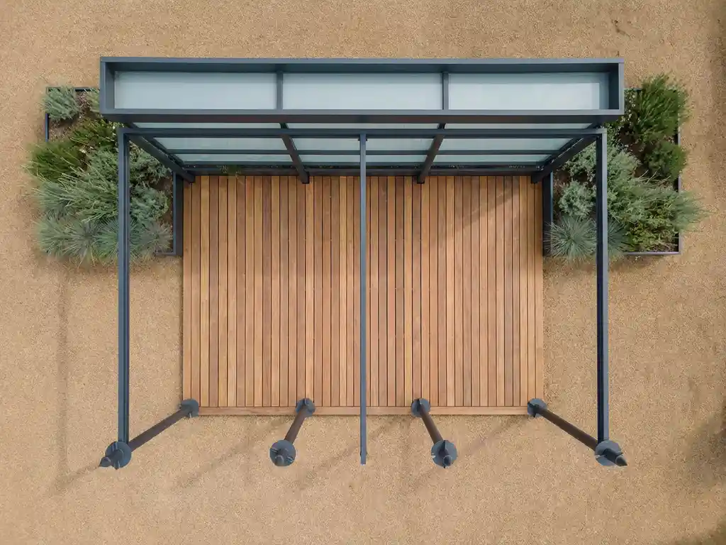 Moderne overdekte terras met stalen schroeffunderingspalen, geometrische houten vlonderplanken en minimalistische overkapping in verzorgde tuin