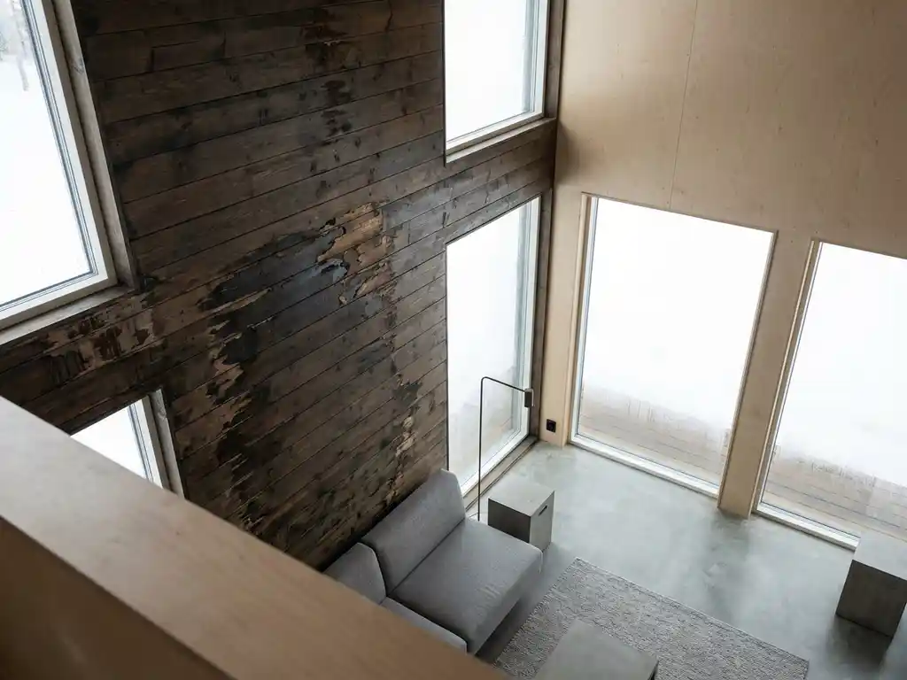 vocht-schade-houten-cabine-moderne-architectuur.jpg Moderne recreatiehut met vochtschade op houten wand, waterdruppels op raam en minimalistische inrichting